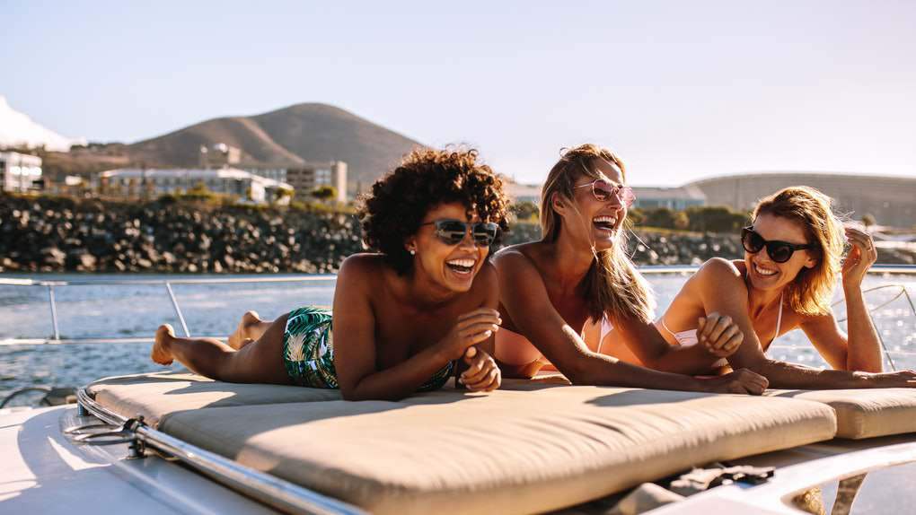 Mensen ontspannen op bootkussens in de zon - Een man en twee vrouwen genieten van de zon op de bootkussens, ontspanning op het water